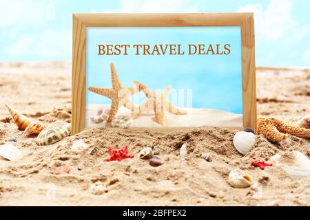 Travel deals concept. Photo frame and seashells on sand, closeup Stock Photo