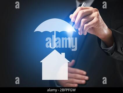 Insurance concept. Businessman drawing umbrella over house, closeup Stock Photo
