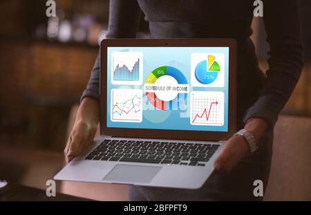 Marketing concept. Woman holding laptop. Schedule of income and business information on screen Stock Photo