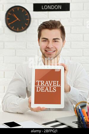 Travel deals concept. Young man holding tablet in office Stock Photo