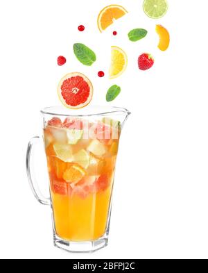 Falling fruit slices and berries into glass jug with lemonade on white background. Recipe for summer drink Stock Photo