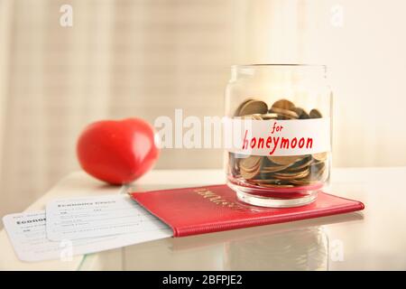 Passport with tickets and money savings for honeymoon in glass jar on table Stock Photo