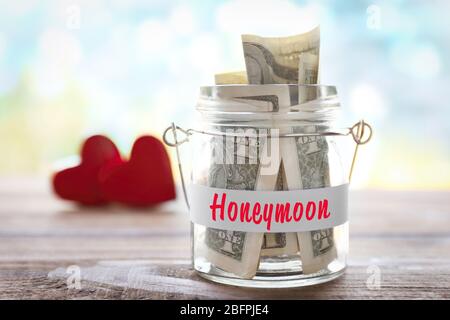Money savings for honeymoon in glass jar on blurred background Stock Photo
