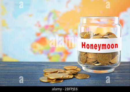 Money savings for honeymoon in glass jar and world map on background Stock Photo