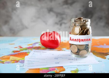 Money savings for honeymoon in glass jar and tickets on world map Stock Photo