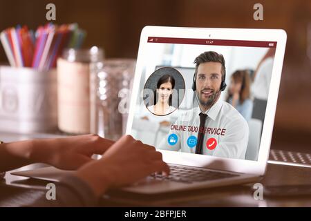 Concept of online taxi service. Woman video conferencing with dispatcher on laptop at table Stock Photo