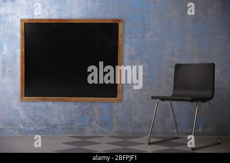 Chair and blank blackboard on wall in empty class room Stock Photo