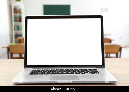 Modern laptop with blank screen on table in classroom Stock Photo