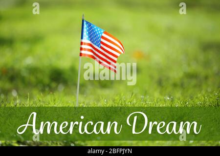 Text AMERICAN DREAM and USA flag on green grass, closeup Stock Photo