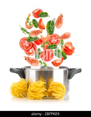 Ingredients falling into saucepan on white background. Tasty pasta recipe Stock Photo