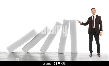 Man trying to stop falling huge dominoes on white background. Leadership concept Stock Photo