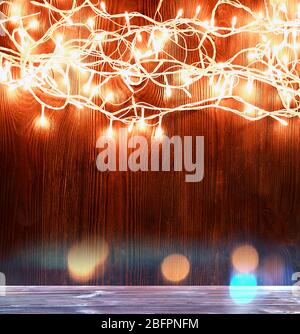 Wooden table and Christmas lights on background Stock Photo