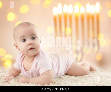 Little child on blurred festive lights background. Baby's First Hanukkah Stock Photo
