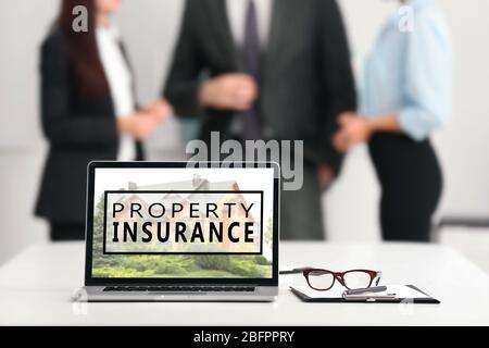 Modern laptop and people on background. Property insurance concept Stock Photo
