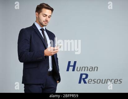 Concept of human resources management. Young businessman with phone on color background Stock Photo