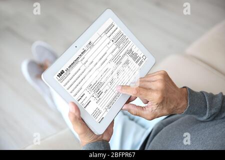 Senior man using tablet for filling in individual income tax return form, closeup Stock Photo