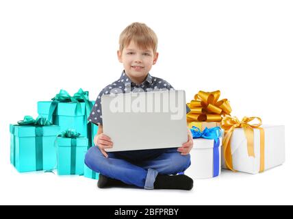Internet shopping concept. Little boy sitting with laptop and gifts on white background Stock Photo