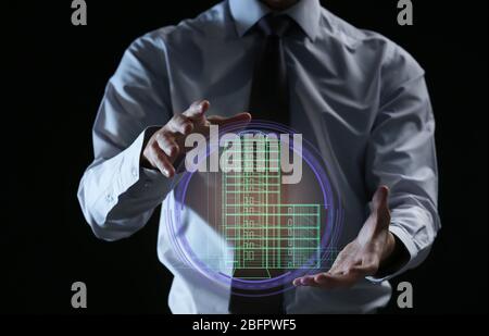 Real estate agent showing projection of building on dark background Stock Photo