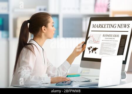 Woman reading marketing news on computer in office Stock Photo