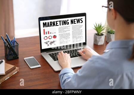 Woman reading marketing news on laptop in office Stock Photo