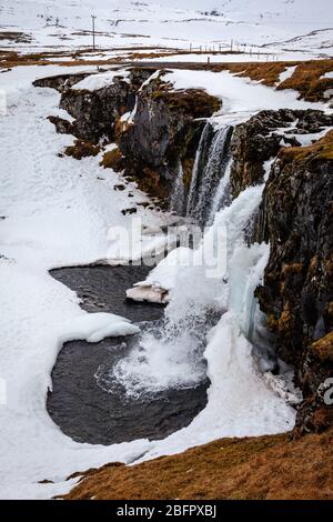 Frozen Kirkjufellsfoss waterfall in south west Iceland on a snowy day in winter Stock Photo