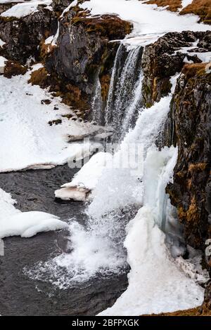 Frozen Kirkjufellsfoss waterfall in south west Iceland on a snowy day in winter Stock Photo