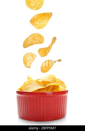 Tasty potato chips falling into bowl on white background Stock Photo