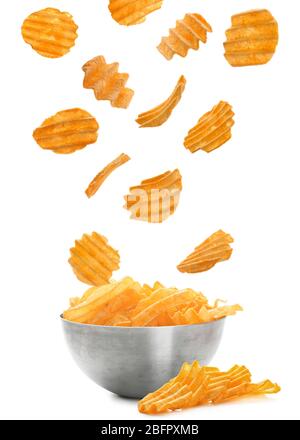 Tasty potato chips falling into bowl on white background Stock Photo