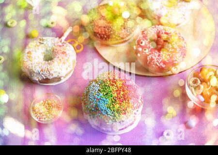 Delicious doughnut decorated with rainbow sprinkles on color background Stock Photo