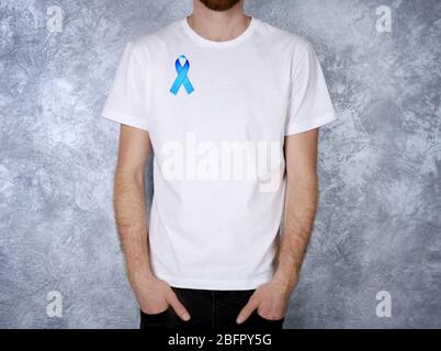 Young man with blue ribbon on color background. Prostate cancer concept Stock Photo
