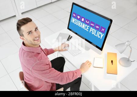 Young man using computer at table. Concept of insurance policy Stock Photo