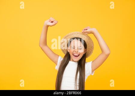 I love it. ready for beach party. small beauty. happy kid dancing on yellow  background. she love summer vacation. spring fashion for kids. childhood  happiness. cheerful little girl wear straw hat Stock