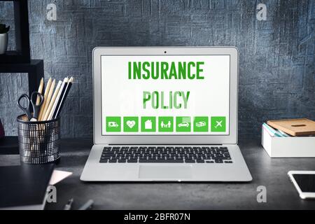 Modern workplace with laptop and text INSURANCE POLICE on screen Stock Photo