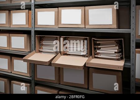 Cardboard boxes with documents on shelving unit in archive Stock Photo