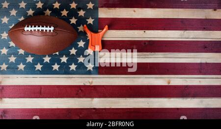 American football with kicking tee on vintage United States wooden flag background. Football sports concept with copy space Stock Photo