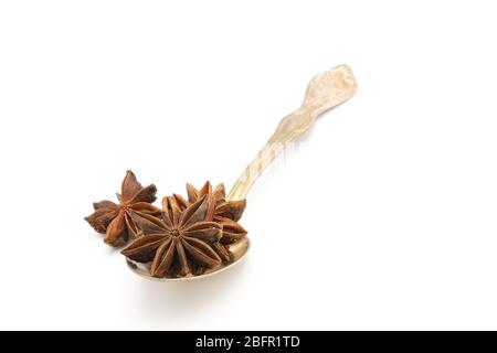 Whole seed pods of star anise, Illicuim verum, in a tarnished vintage antique spoon on a white background with ample copy spave. Stock Photo