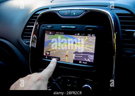 A close up of a finger operating a sat nav or satellite navigation unit inside a car Stock Photo