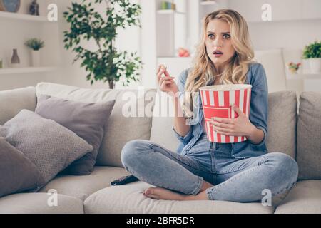 Photo of beautiful crazy terrified barefoot lady sitting comfy couch eat popcorn legs crossed watch horror scary movie eyes full fear stay home good Stock Photo