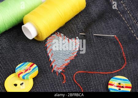 Heart-shaped patch on jeans with threads and buttons closeup Stock Photo