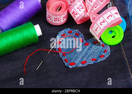 Heart-shaped patch on jeans with threads and buttons closeup Stock Photo