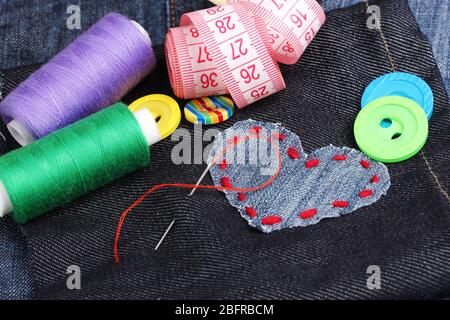 Heart-shaped patch on jeans with threads and buttons closeup Stock Photo