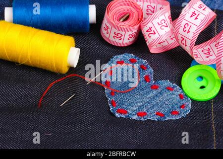 Heart-shaped patch on jeans with threads and buttons closeup Stock Photo