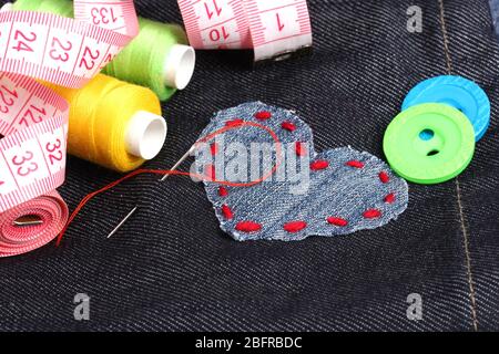 Heart-shaped patch on jeans with threads and buttons closeup Stock Photo