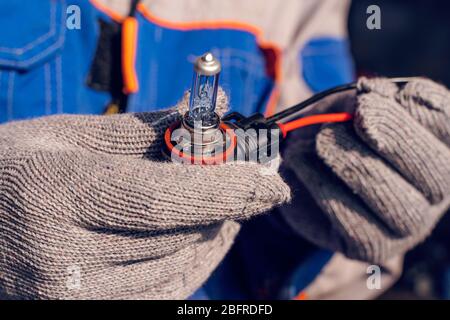 Car service men. Replacing a burnt out lamp in the car headlight Stock Photo