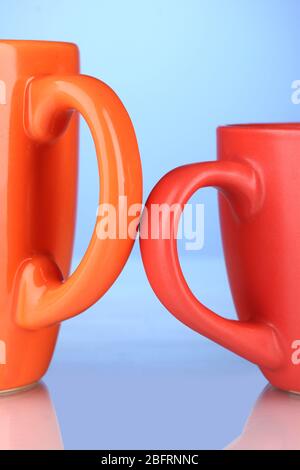 Two colored cups handles close-up on blue background Stock Photo
