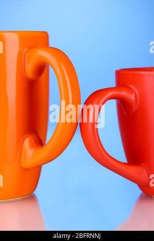 Two colored cups handles close-up on blue background Stock Photo