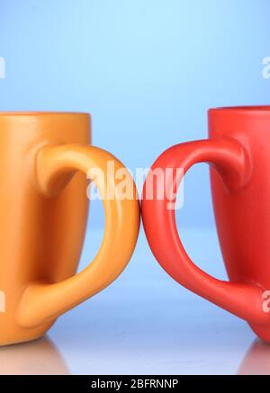 Two colored cups handles close-up on blue background Stock Photo