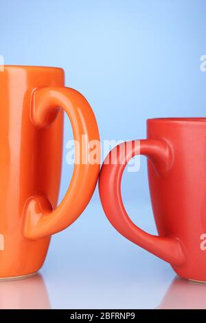 Two colored cups handles close-up on blue background Stock Photo