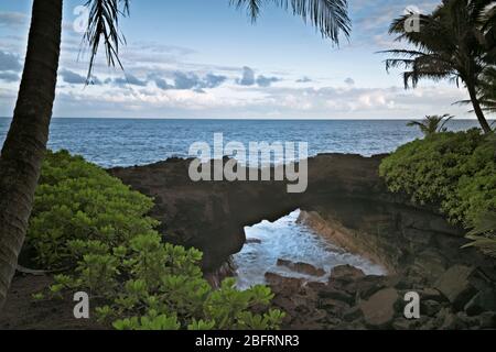 The Pacific Ocean rushes into this natural lava arch along the Puna coastline on the Big Island of Hawaii. Stock Photo