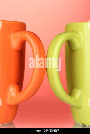 Two colored cups handles close-up on red background Stock Photo